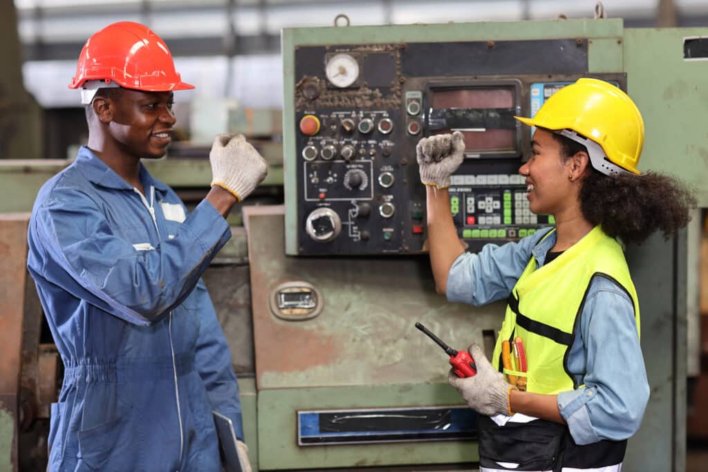 Happy smiling teamwork technician engineer or worker in protective uniform with hardhat doing fist bump celebrate successful together completed deal commitment at heavy industry manufacturing factory